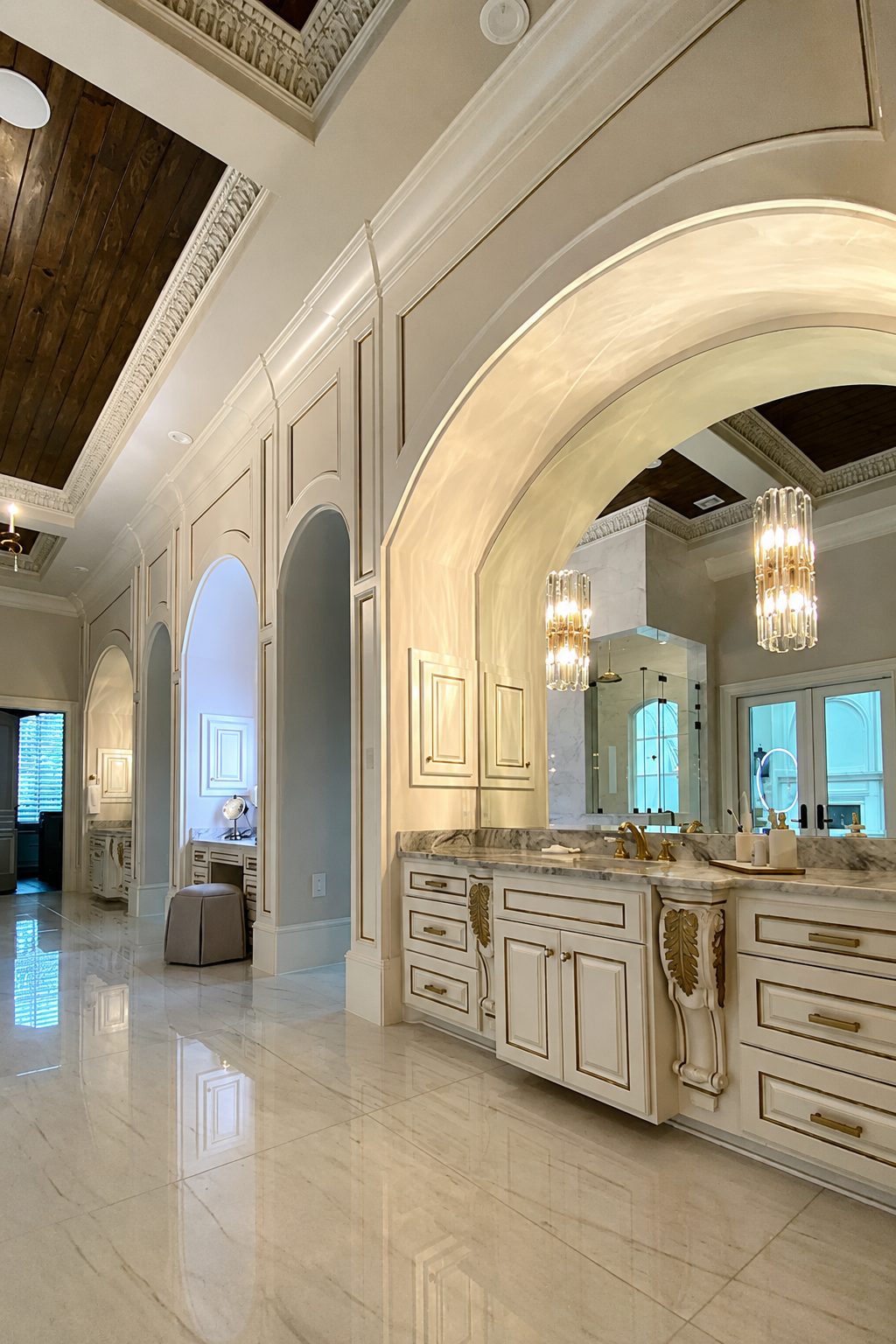 Cream glazed cabinetry and a built-in vanity beside a grand arched hallway