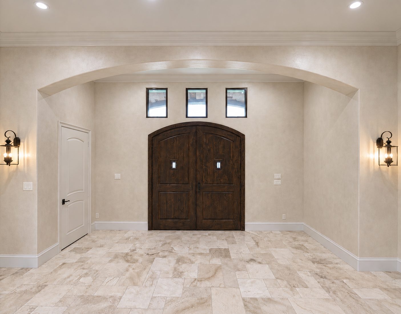 Arched wood double doors in an entry finished in hand-applied Venetian plaster