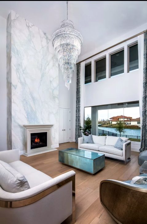 White marble look fireplace beneath a chandelier