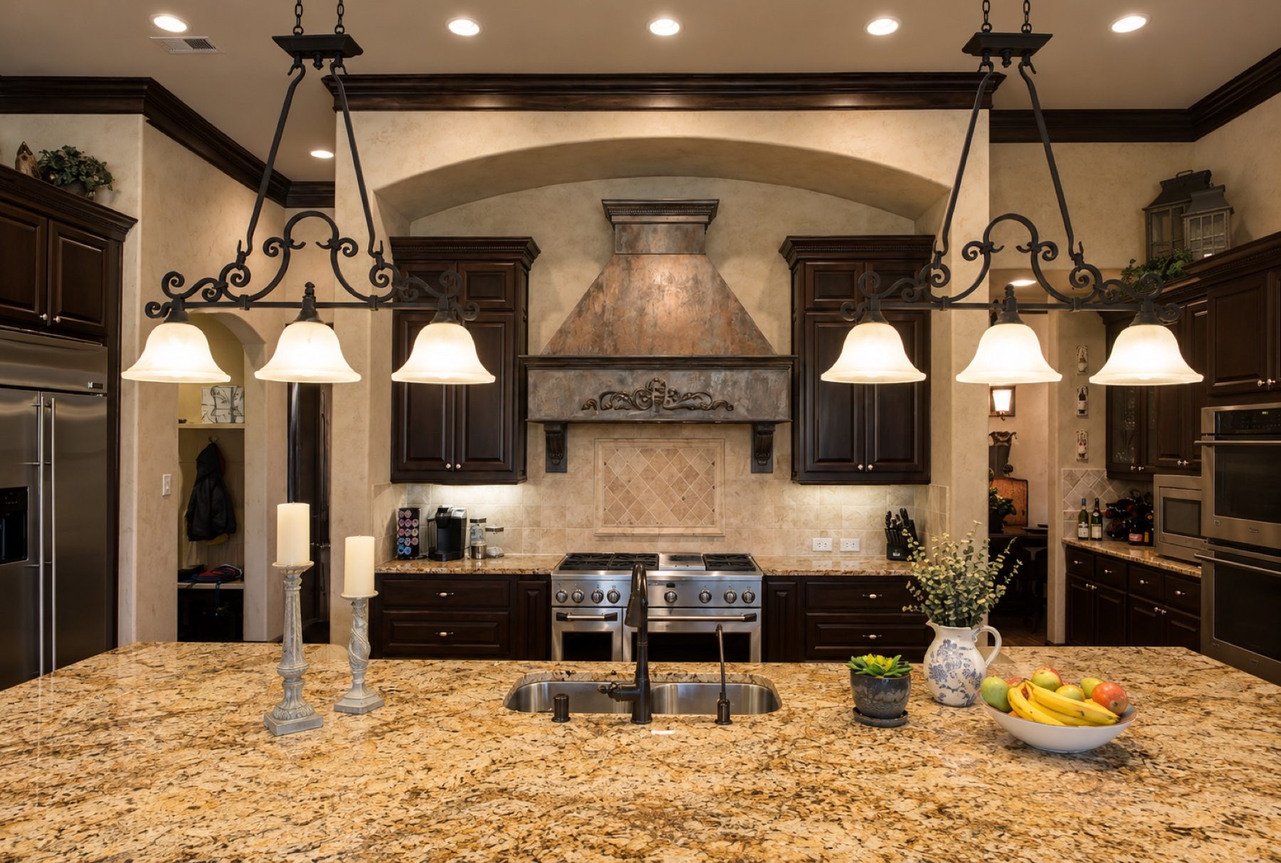 Kitchen range hood finished in copper-toned decorative plaster beneath an arched alcove